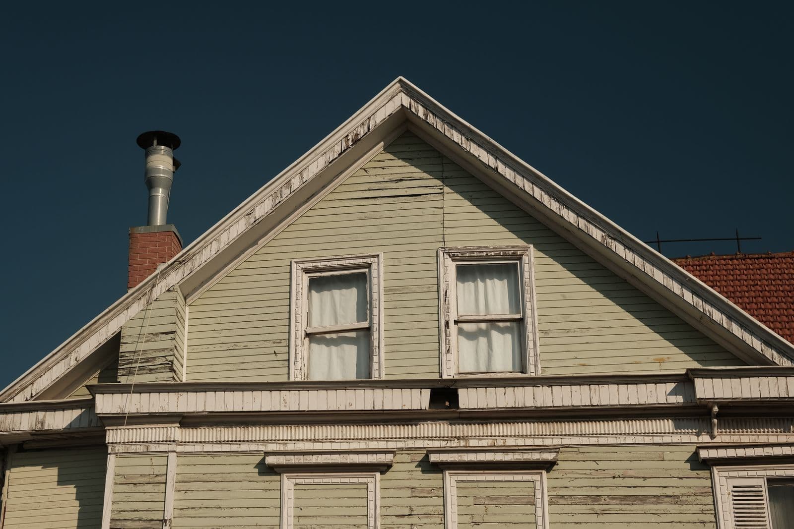 Gable and chimney of an old house clad in weathered wood siding