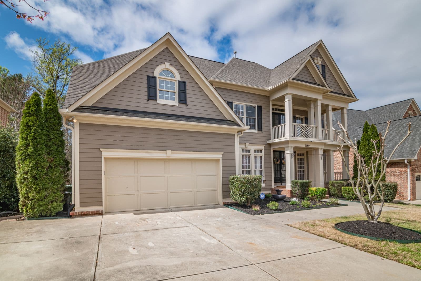 Two-story house with tan siding, gables and a two-car garage