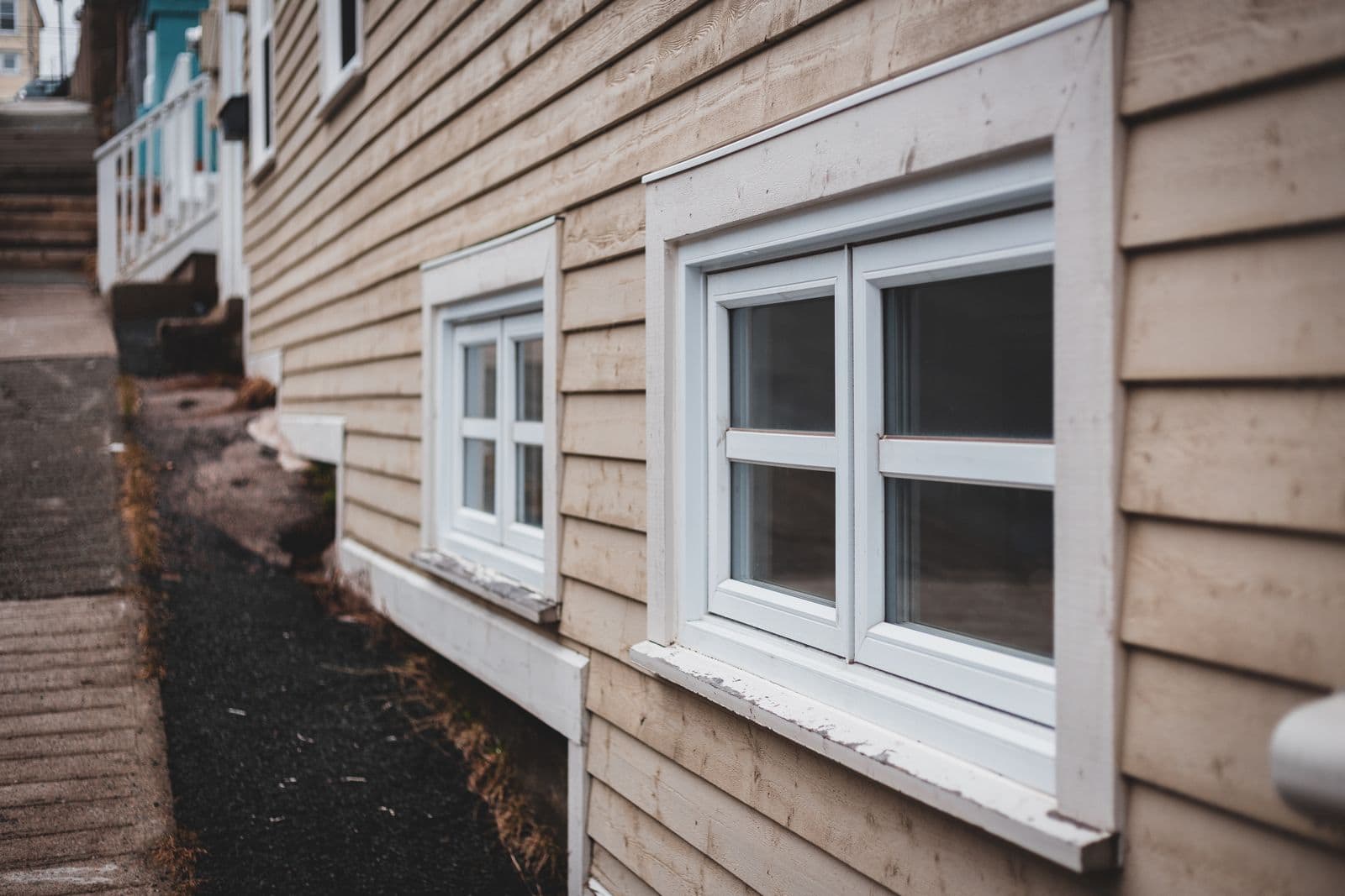 Beige lap siding on a house wall with white-framed windows
